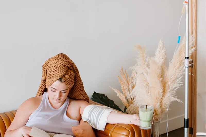 Mobile IV therapy in California Heights, CA by Lively Drops, a client reading while an IV drip runs beside her